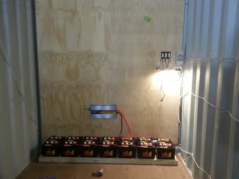 A plywood mounting wall installed behind the batteries and power equipment.