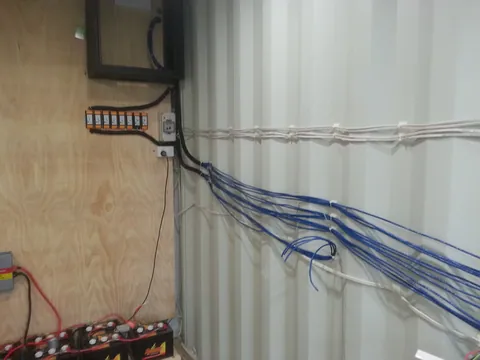 Blue data cables gathered beneath the wall cabinet.
