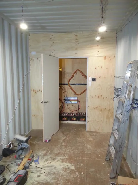 The partition lined in plywood, separating the service area.