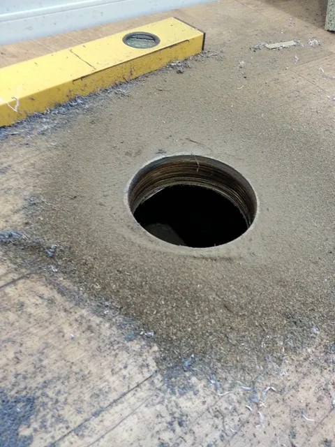 A circular opening prepared through a cabinet panel.