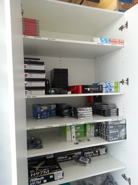 Computer parts organised on the cabinet shelves.