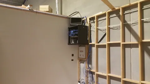 A timber partition takes shape beside existing wiring and wall panels.
