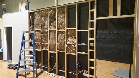 Insulation work moves around the adjacent wall.