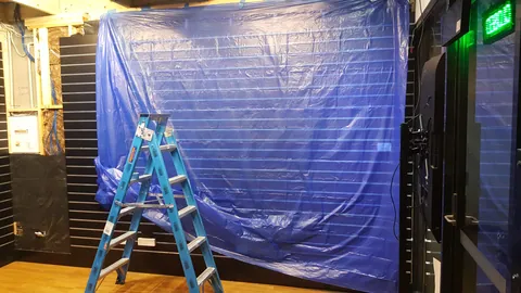 Protective sheeting covers the room during painting.