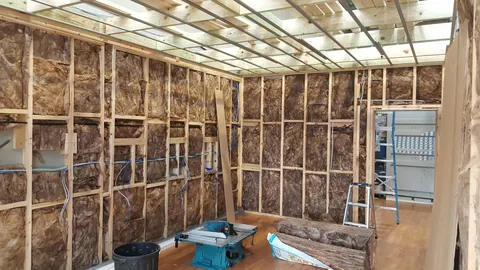 An adjacent area still has exposed insulation and framing.