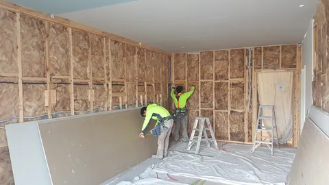 The wall lining is measured and fitted around the remaining exposed insulation.