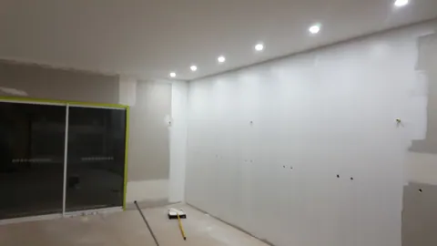 White paint starts covering the prepared wall.