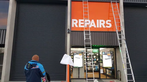 The orange sign is installed above the shopfront, with ladders still in place.