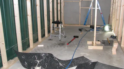 The compact room begins as exposed timber framing above a bare floor.