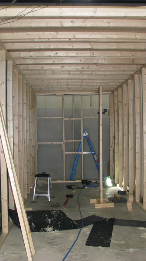 Wall studs and ceiling joists define the long, narrow room.