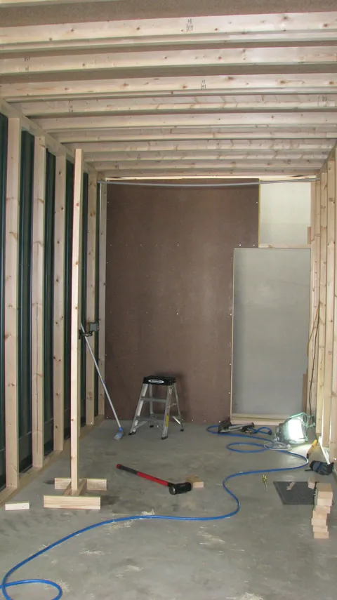 More wall panels are fitted while the ceiling framing remains exposed.