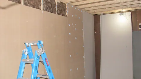 Wall panels cover more of the framing, with insulation still visible above.