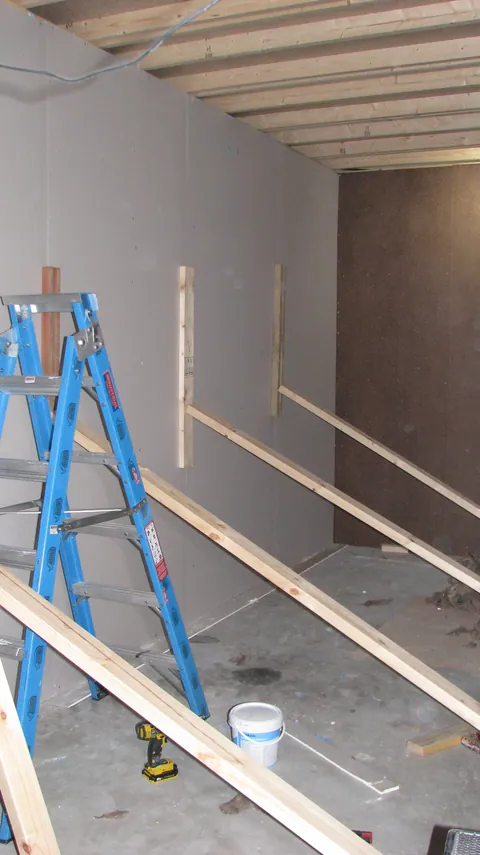 Horizontal timber pieces are fitted across the partly lined wall.
