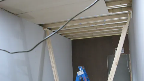 Ceiling lining starts covering the exposed joists.