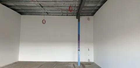 The empty premises, with the roof structure exposed and the blue shopfront frame in place.