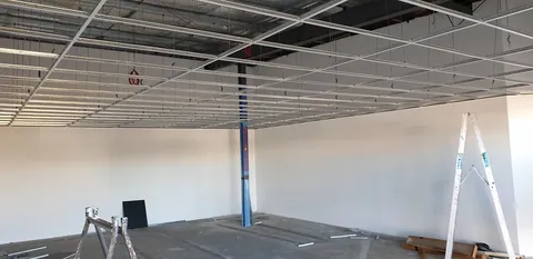The first suspended-ceiling grid installed at the back.