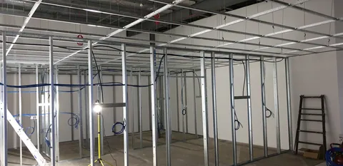 The framed rooms and cabling during an evening of construction.
