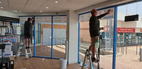 Brand signage being applied inside the front windows.