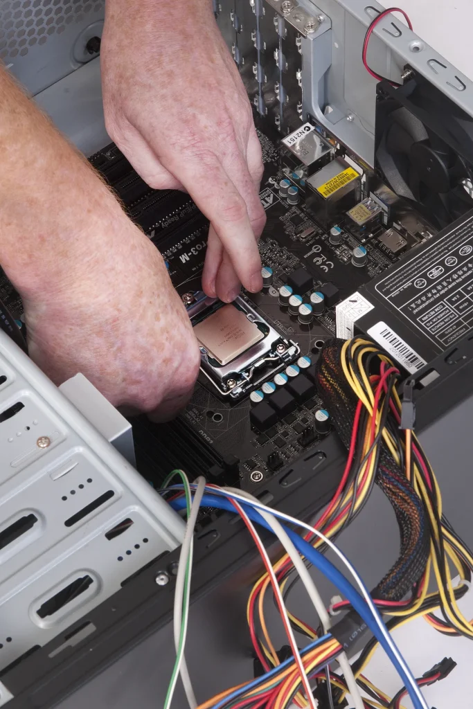 Hands working on the processor and motherboard inside an open desktop computer
