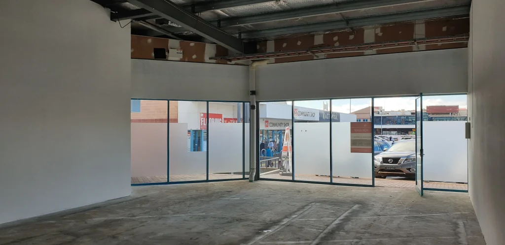 View across the empty concrete-floored premises towards the blue-framed glass shopfront at Homeworld