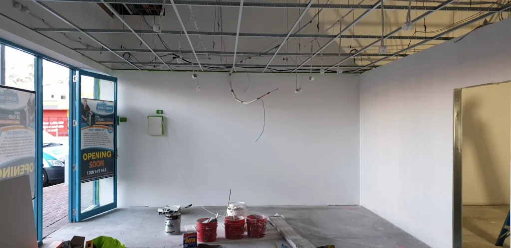 White-painted showroom walls, paint tins and an unfinished suspended ceiling