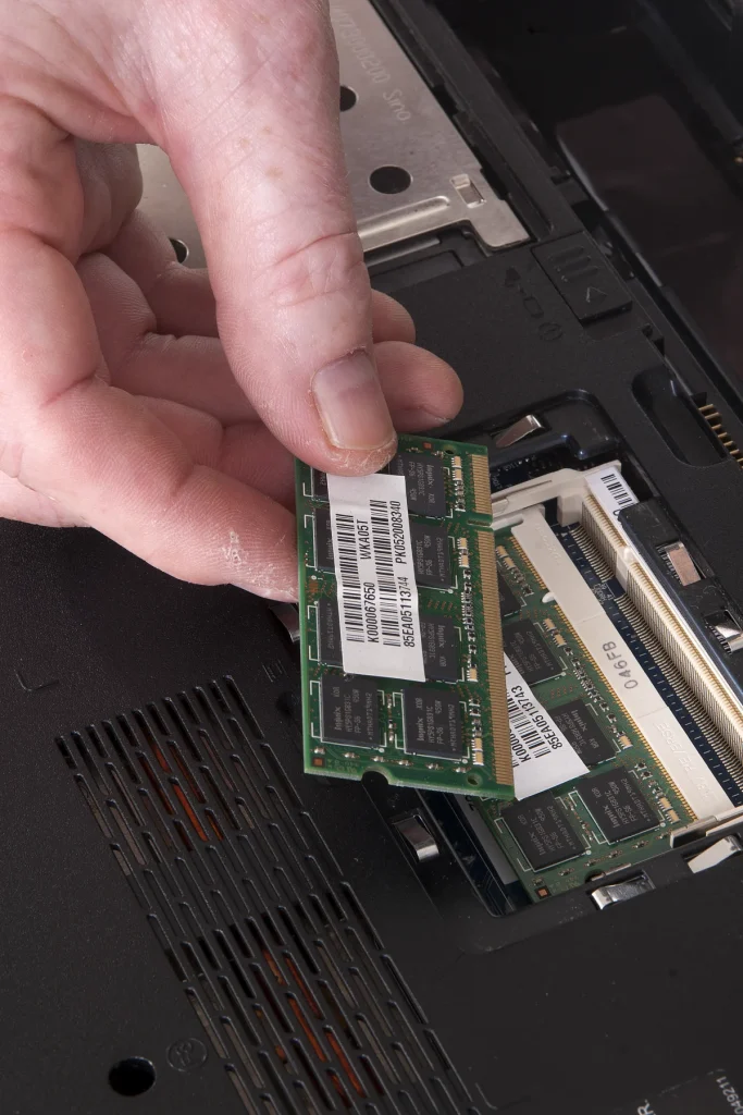 Hands fitting memory into an open laptop