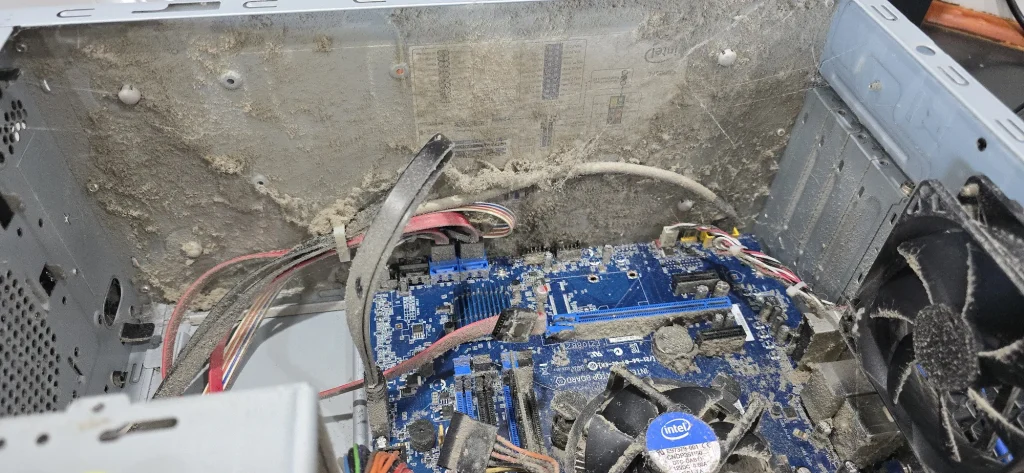 Heavy dust and cobwebs covering the inside of a desktop computer, its cables, motherboard and cooling fans